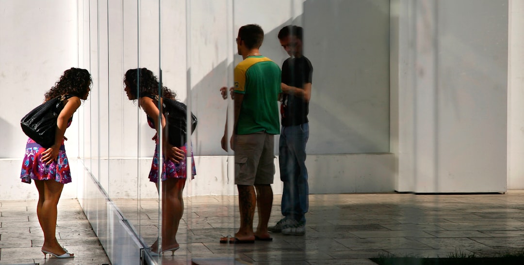 reflection of two men on the mirror and woman standing in front of the mirror